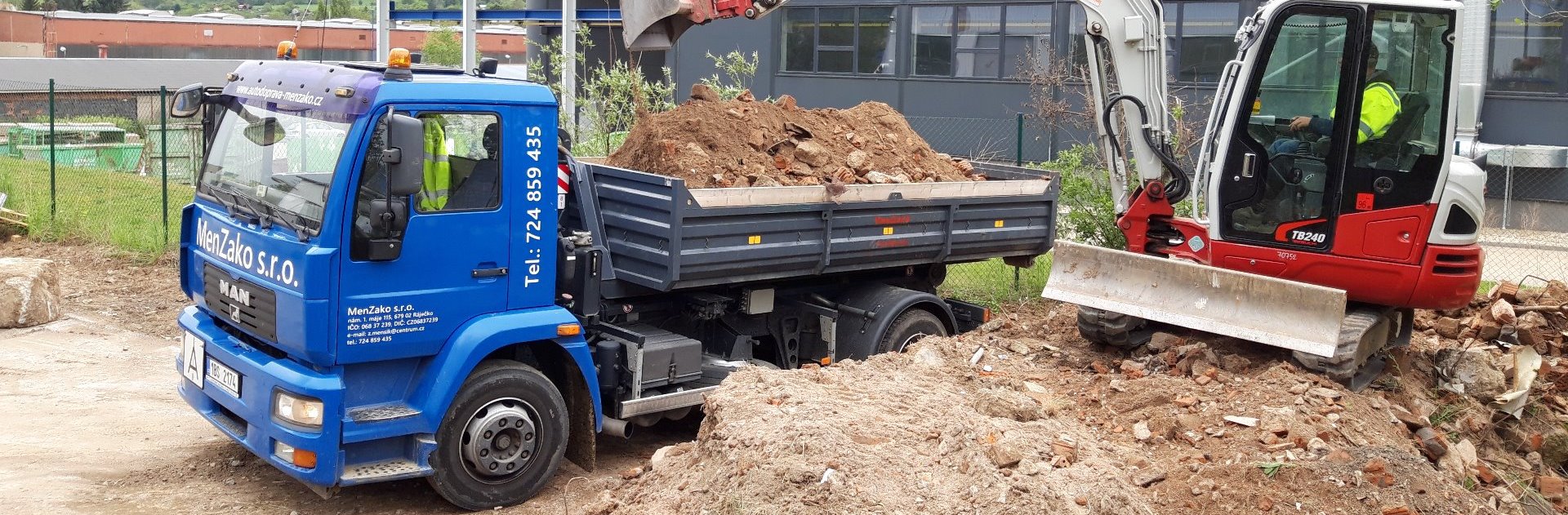 Modrý vůz MAN a červený bagr při výkopových pracích
